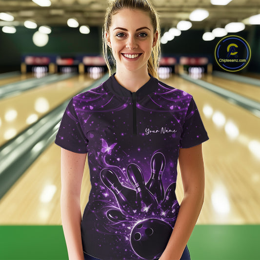 Female model wearing a black and purple bowling quarter-zip shirt at the bowling lane with glowing butterflies, bowling pins, and ball graphics.
