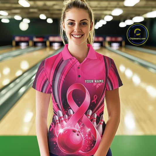 Female model wearing a pink and black bowling polo with breast cancer awareness ribbons and bowling artwork, front view inside a bowling alley