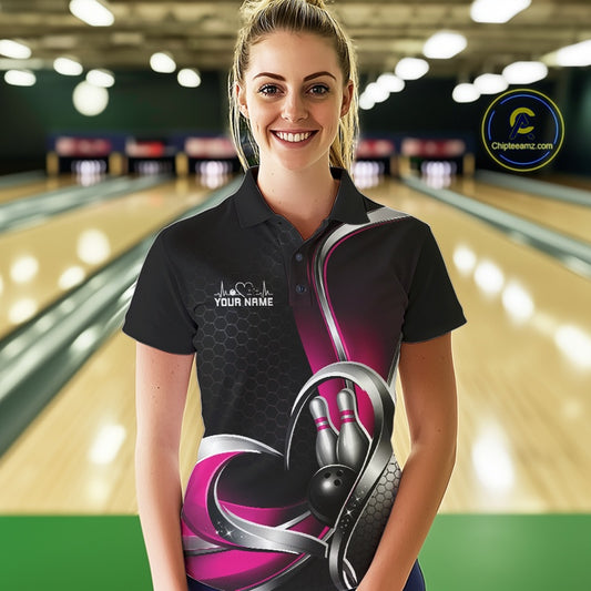 Female model in a bowling alley wearing a black and pink polo shirt with honeycomb texture and a heart-framed bowling strike graphic.