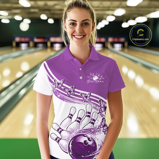 Front view of a female model wearing a white and purple bowling polo with butterfly artwork and bowling graphics inside a bowling center