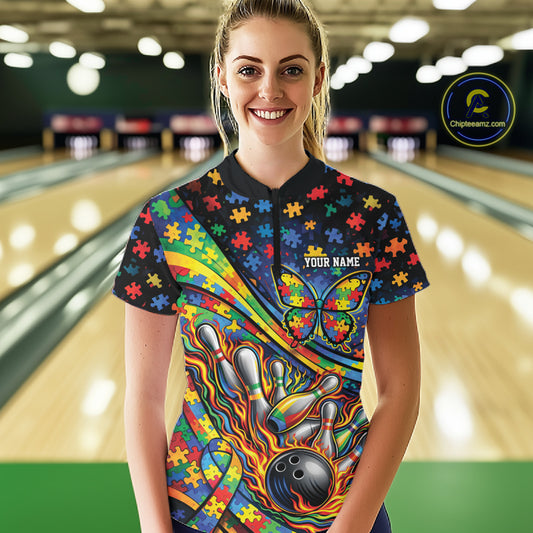 Female model in a bowling lane wearing a colorful quarter-zip shirt, autism awareness bowling ribbon and butterfly with flame bowling accents.