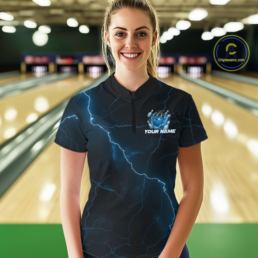 Female model at the bowling lane wearing a black and blue quarter-zip with fantasy dragon claw bowling graphics.