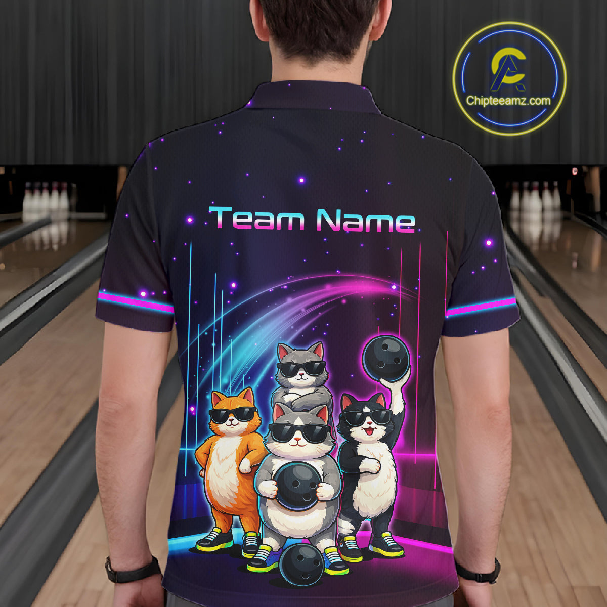 Person wearing a bowling shirt with cartoon cats and 'Team Name' text in a bowling alley.