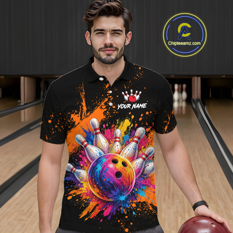 A man wearing a black short-sleeve polo shirt with a colorful bowling-themed graphic print, standing in a bowling alley. The shirt features a vibrant multicolor bowling ball and pins design on the front, with a white crown logo and the text 'YOUR NAME' on the chest.