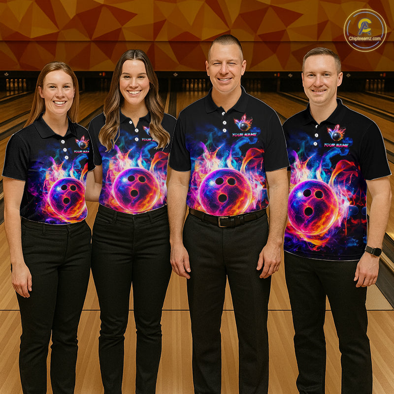 Four people standing together in a bowling alley wearing matching black polo shirts with a vivid cosmic bowling graphic and black pants. The shirts feature a colorful design with a purple bowling ball, pink and blue flames.