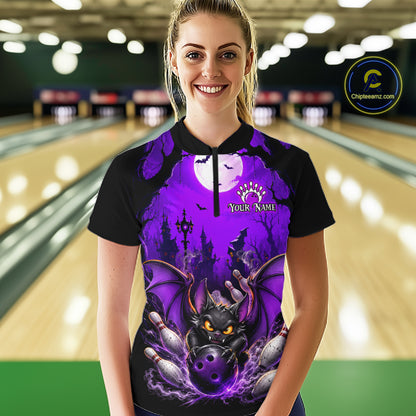 A woman wearing a black and purple Halloween-themed bowling bowling shirt stands in a bowling alley. The shirt features a graphic of a black bat with glowing yellow eyes, bowling pins, and a full moon under a purple sky, with 'Your Name' printed on the chest.