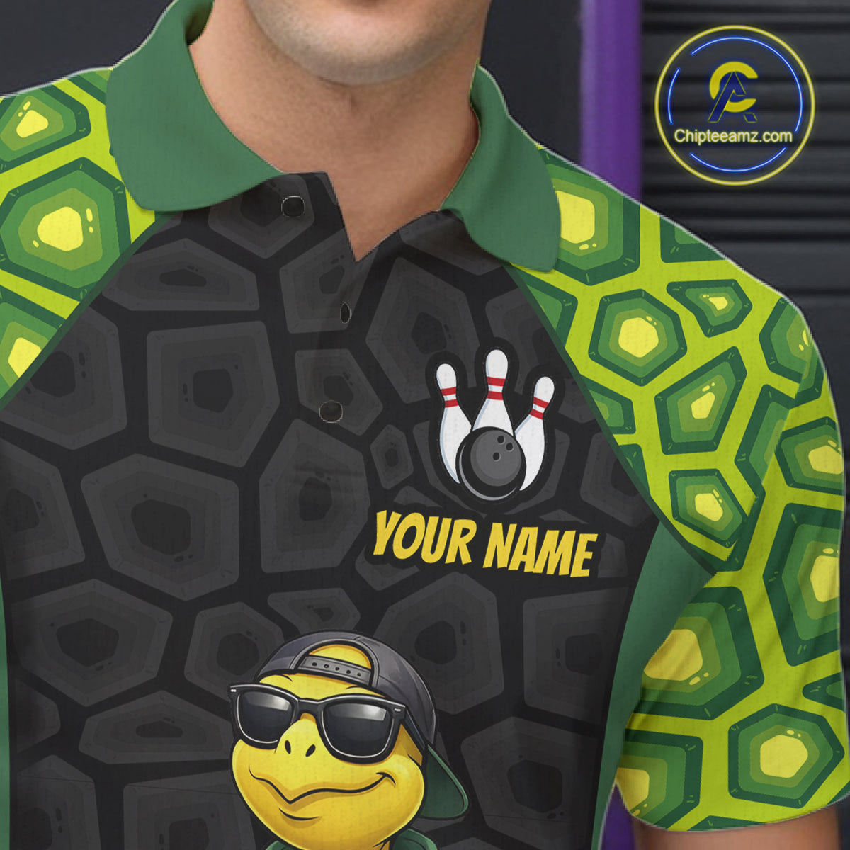A close-up of a custom printed polo shirt worn by a model. The shirt features a black and dark gray turtle-shell pattern on the body, green collar and sleeve cuffs, and a lime green patterned design on the sleeves.