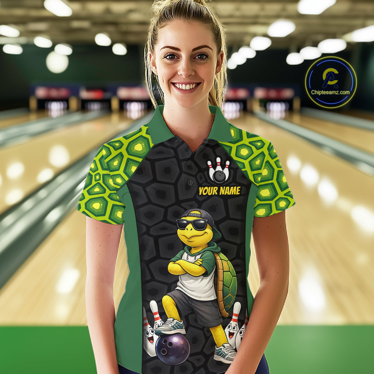 A woman stands in a bowling alley wearing a custom short-sleeve bowling shirt with a turtle graphic and 'YOUR NAME' printed on the front. The shirt features green and black turtle-scale patterns on the sleeves and shoulders, with a black center panel showing a cartoon turtle wearing sunglasses and bowling accessories.