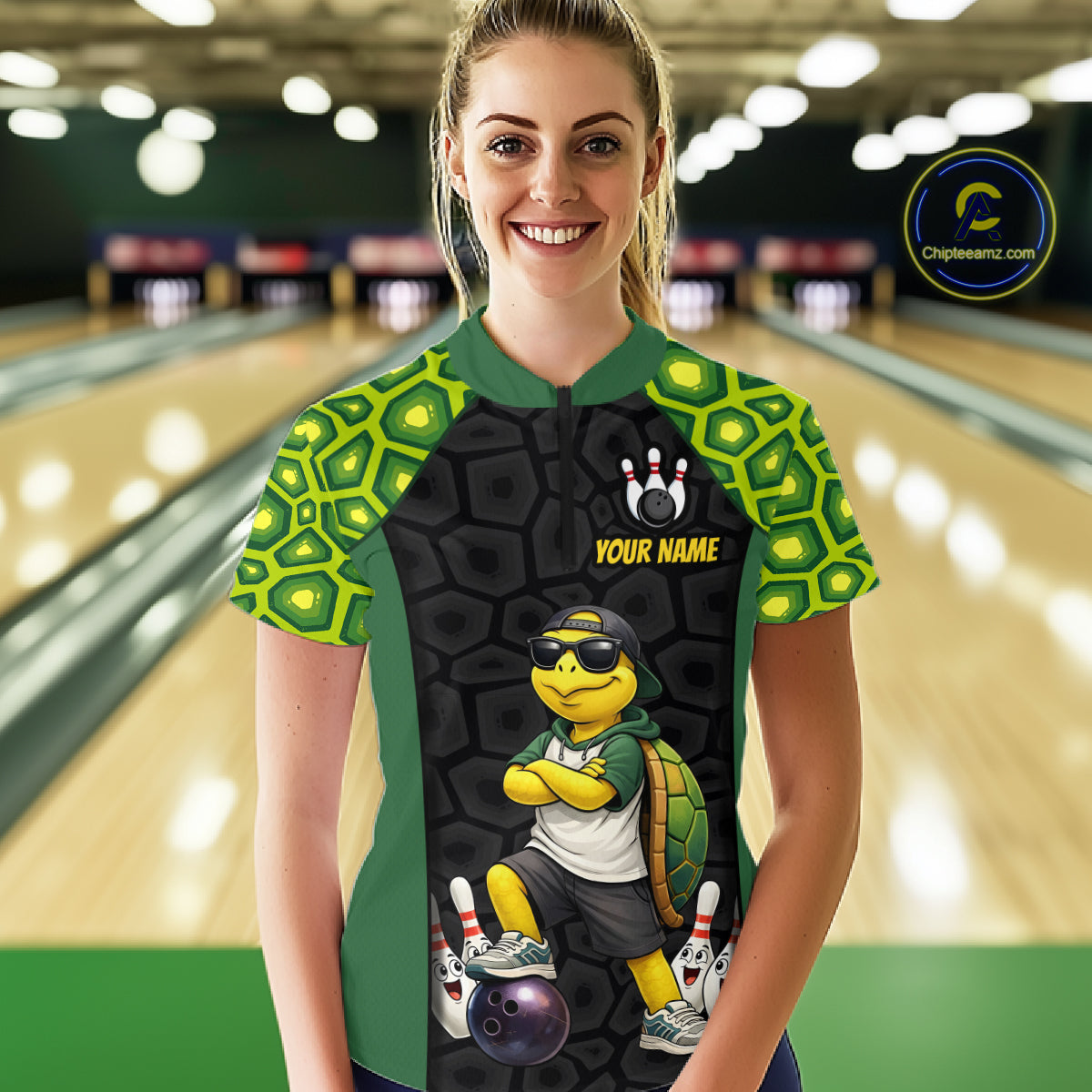 A woman stands in a bowling alley wearing a custom bowling shirt. The quarter-zip shirt features a black and green turtle shell pattern, a cartoon turtle graphic, and the text 'YOUR NAME'.
