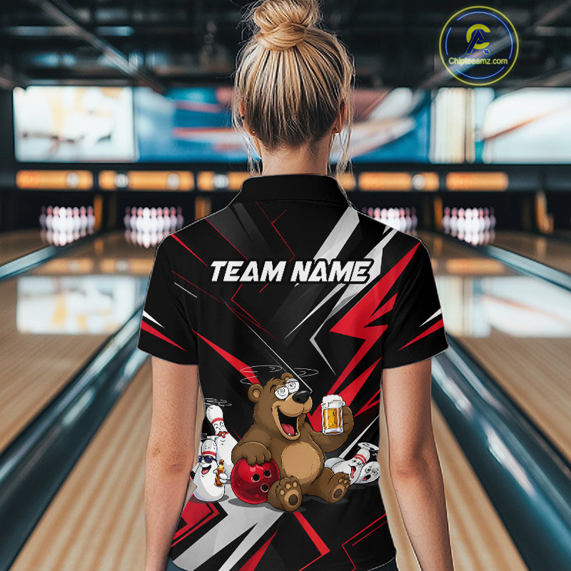 Person wearing a bowling shirt with a bear design and 'TEAM NAME' text in a bowling alley.