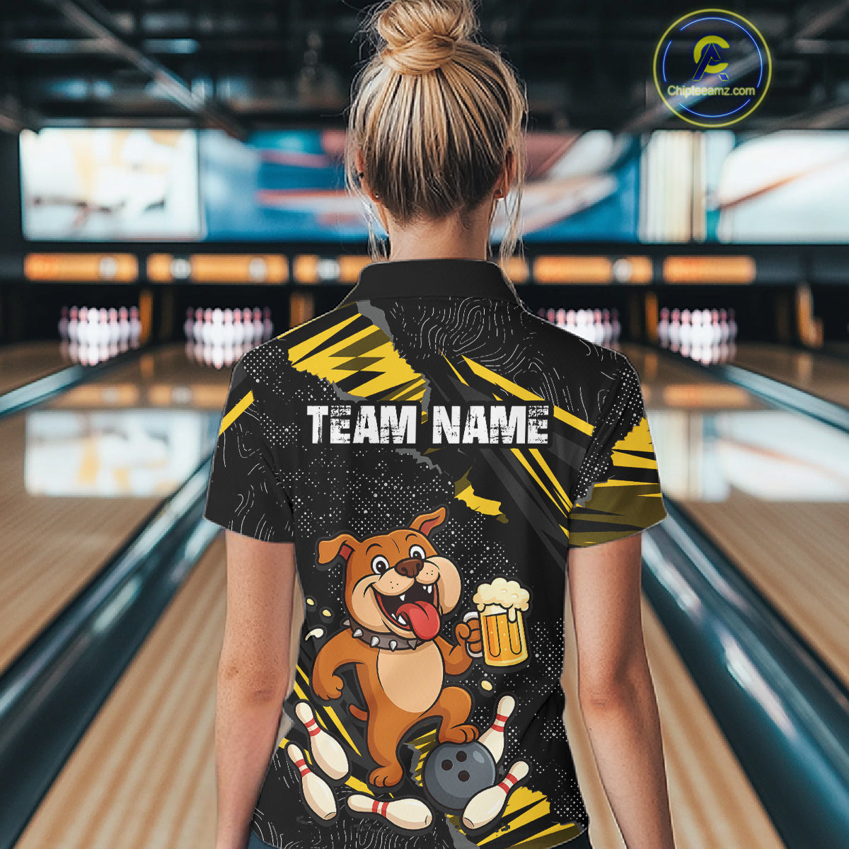 A woman wearing custom black yellow bulldog bowling polo shirt back view featuring a bowling ball, beer mug and yellow paint splash pattern, displaying Team Name, at the bowling alley