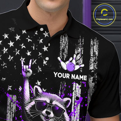 Black polo shirt with a raccoon, hand, and bowling ball design on a dark background
