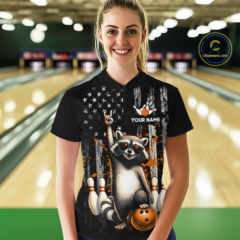 Person wearing a black shirt with a raccoon graphic and 'Your Name' text in a bowling alley.