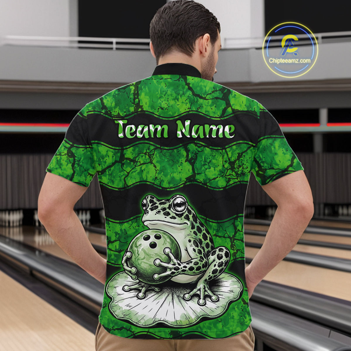 A man viewed from behind wearing a short-sleeve bowling shirt with a green and black frog graphic holding a bowling ball, with the text 'Team Name' across the upper back. Bowling lanes are visible in the background, and a 'ChuteStream3.