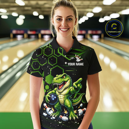 A woman wearing a black and green bowling-themed polo shirt with a dinosaur graphic, standing in a bowling alley. The shirt features a green T-Rex holding bowling balls, green hexagonal patterns, and a customizable name print area.