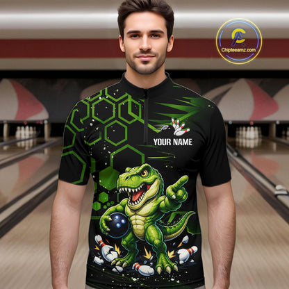 A man wearing a black short-sleeve bowling jersey with a green cartoon dinosaur graphic, bowling pins, and the text 'YOUR NAME' on the chest. The background shows a blurred bowling alley.