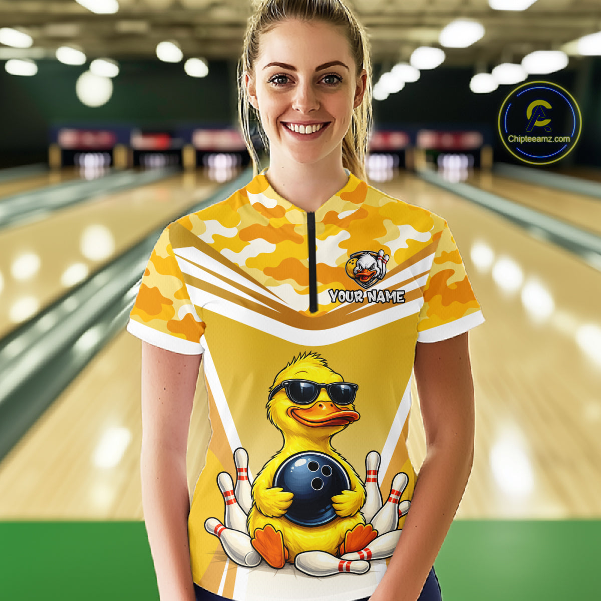 Female model wearing a custom yellow duck bowling quarter-zip shirt front view featuring a cool cartoon duck wearing sunglasses, bowling ball, bowling pins and yellow camouflage pattern at the bowling alley