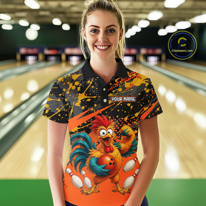 Female model wearing a custom orange rooster bowling polo shirt front view featuring a fierce cartoon rooster, bowling ball, bowling pins and black yellow paint splatter pattern at the bowling alley