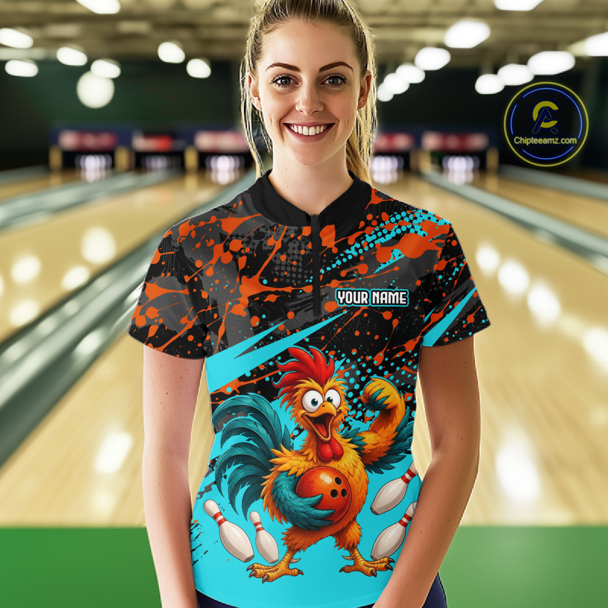 Female model wearing a custom black turquoise rooster bowling polo shirt front view featuring a fierce cartoon rooster, bowling ball, bowling pins and turquoise orange paint splash pattern at the bowling alley
