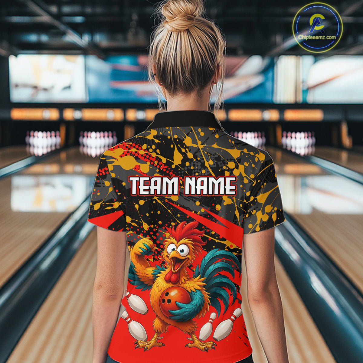 Female model wearing a custom black red rooster bowling polo shirt back view displaying the personalized team name above a fierce cartoon rooster graphic at the bowling alley