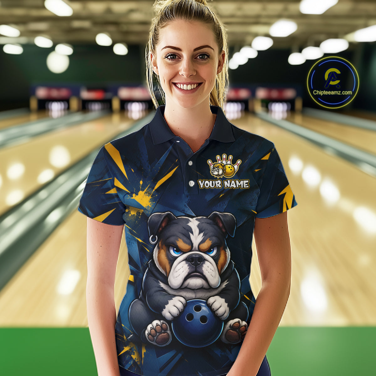 Female model wearing a custom blue bulldog bowling polo shirt front view featuring a fierce cartoon bulldog, bowling ball, gold lightning accents and navy blue abstract pattern at the bowling alley
