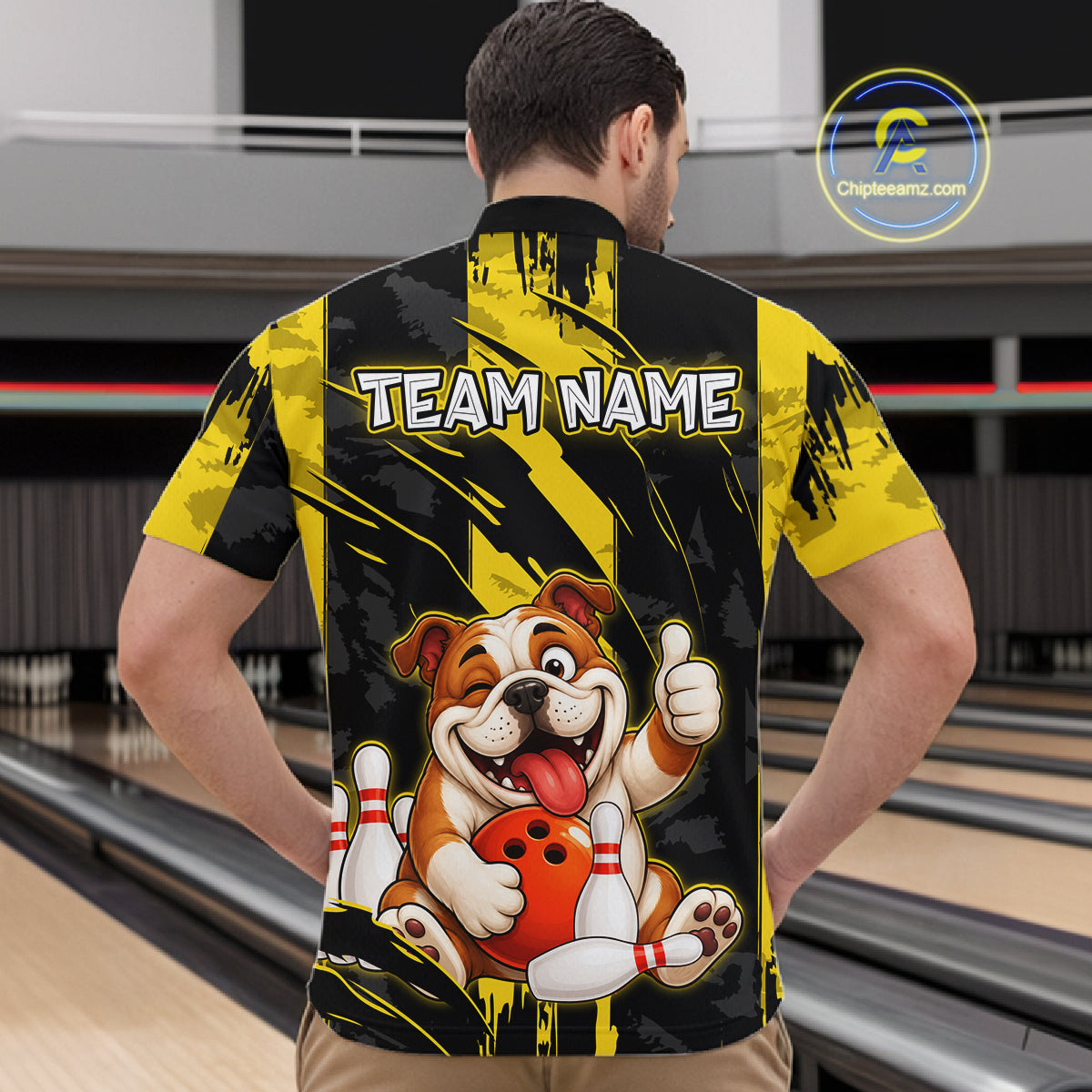Male model wearing a custom black yellow bulldog bowling quarter-zip shirt back view displaying the personalized team name above a playful cartoon bulldog graphic at the bowling alley