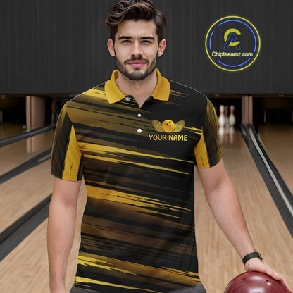 Male model wearing a custom black gold bowling polo shirt front view featuring a gold bowling ball emblem, dynamic gold brush stroke pattern and striped design at the bowling alley