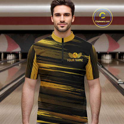 Male model wearing a custom black gold bowling quarter-zip shirt front view featuring a gold bowling ball emblem, dynamic gold brush stroke pattern and striped design at the bowling alley