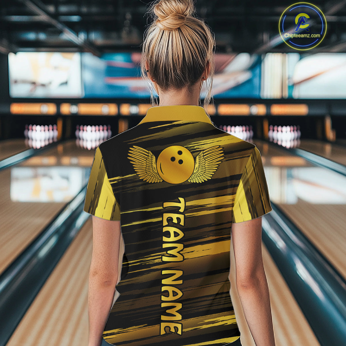 Female model wearing a custom black gold bowling polo shirt back view displaying the personalized team name below a gold bowling ball emblem at the bowling alley