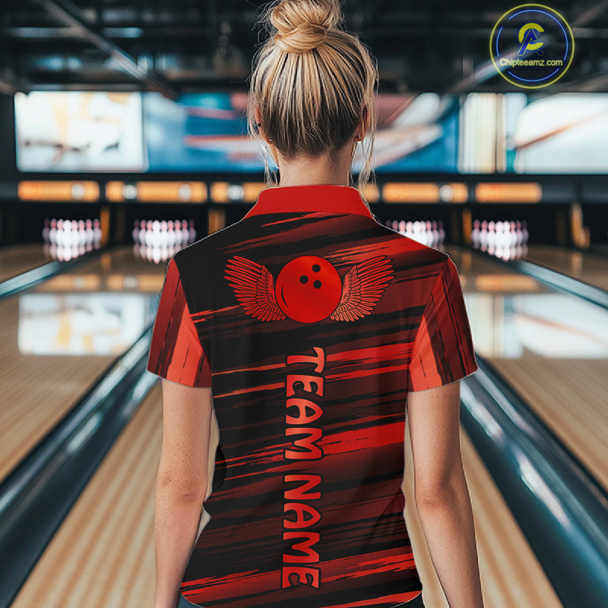 Female model wearing a custom black red bowling polo shirt back view displaying the personalized team name below a red bowling ball emblem at the bowling alley