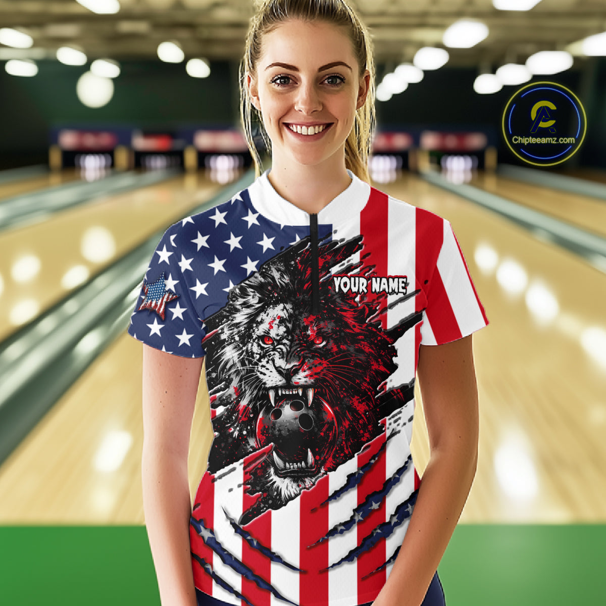 Woman wearing a patriotic-themed bowling shirt with a lion design in a bowling alley.