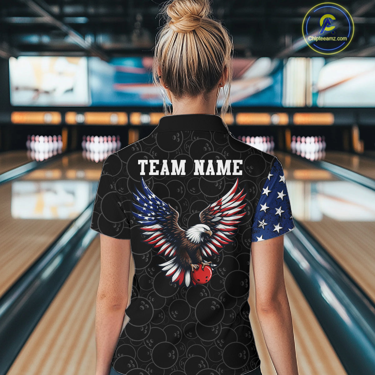 Person wearing a black shirt with an eagle design and 'TEAM NAME' text in a bowling alley.