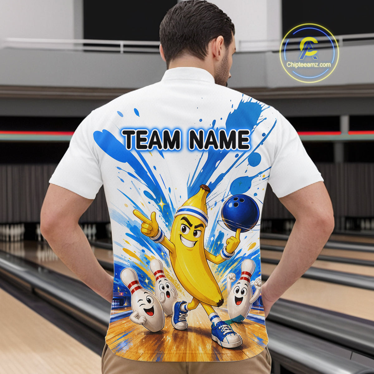 Person wearing a white shirt with a colorful design of a banana character and bowling elements, with 'TEAM NAME' text on the back, in a bowling alley.
