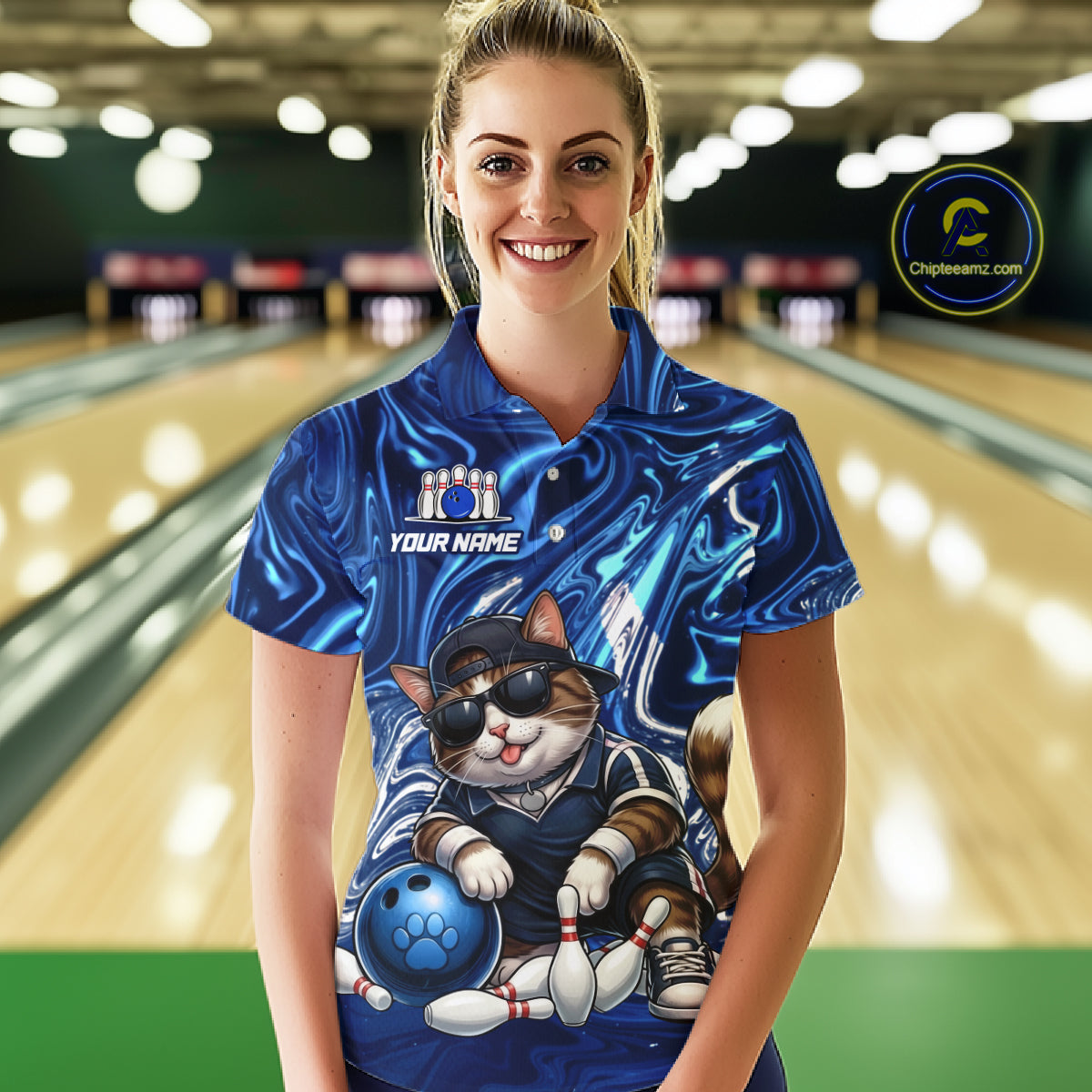 Person wearing a blue bowling shirt with a cat design in a bowling alley.
