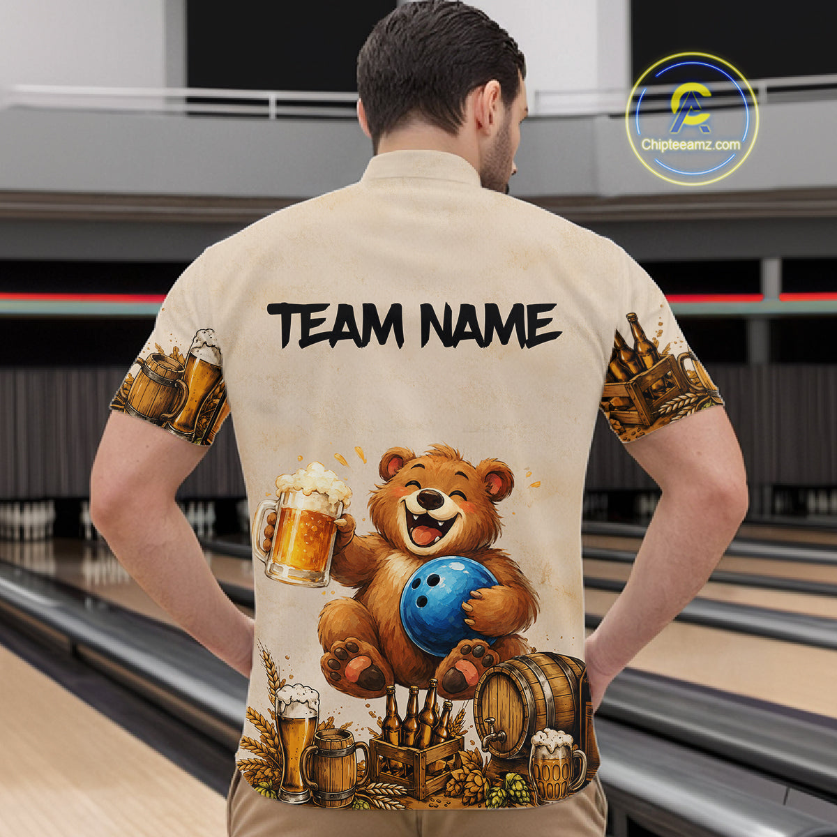 Man wearing a bowling-themed shirt with a bear holding a bowling ball and beer mugs in a bowling alley.