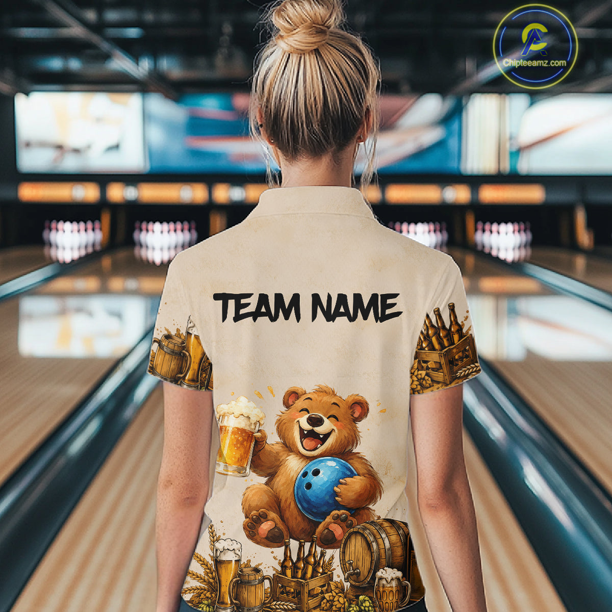 Person wearing a shirt with a bear holding a bowling ball design in a bowling alley.