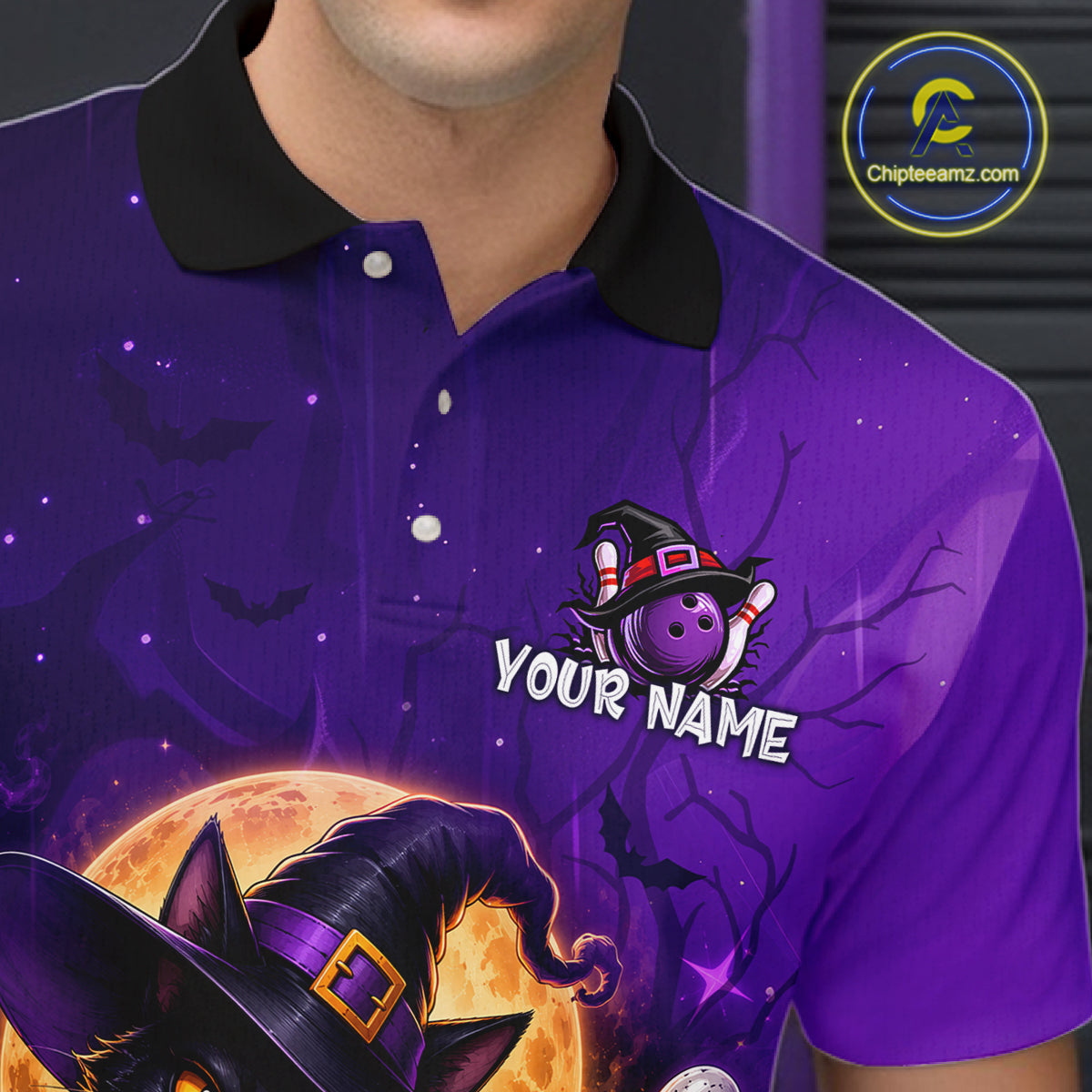 A close-up of a person wearing a purple Halloween-themed polo shirt with a black collar. The shirt features a graphic of a witch hat over a cat's face, a purple bowling ball, and the text 'YOUR NAME' on the chest.