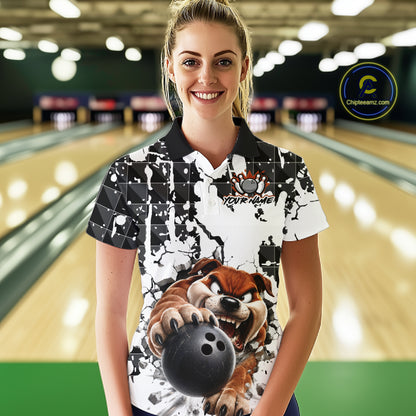 Woman wearing a bowling shirt with a cartoon character holding a bowling ball in a bowling alley.