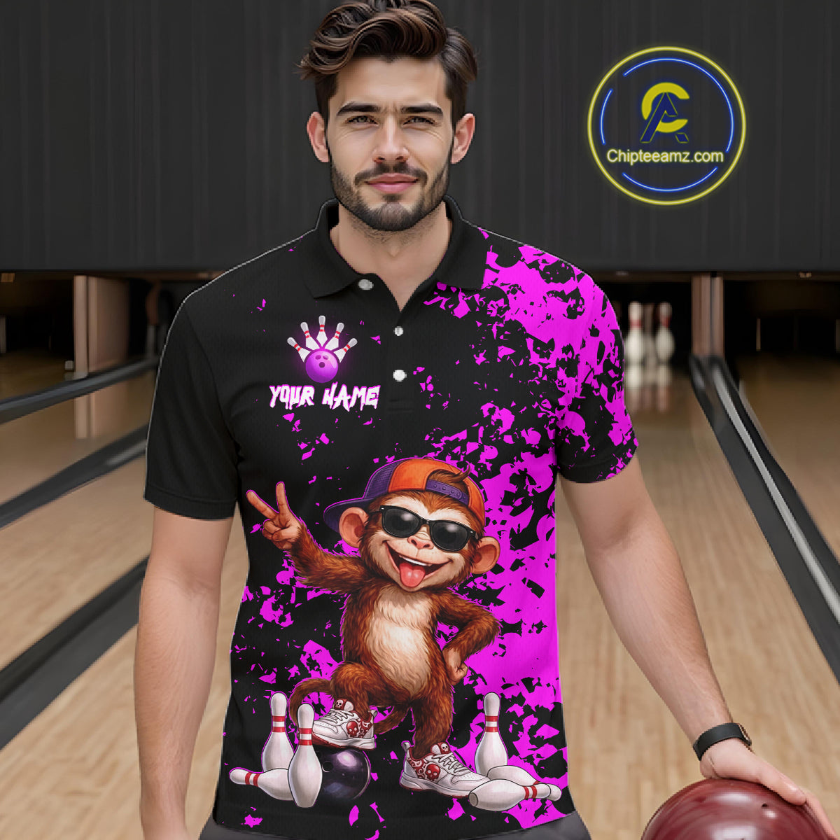 A man wearing a black and bright purple bowling-themed graphic polo shirt with a cartoon monkey design, standing in a bowling alley. The shirt features a purple bowling pin graphic, the text 'YOUR NAME'  and a purple splatter pattern.