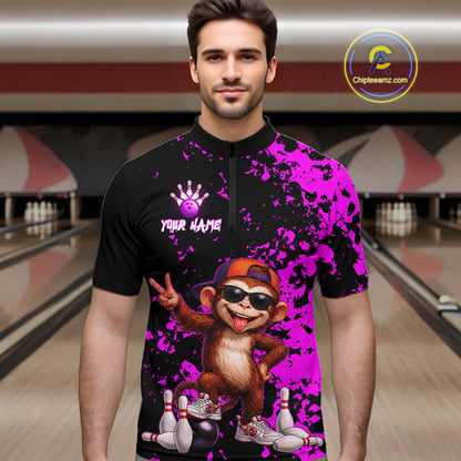 A man wearing a custom bowling-themed short-sleeve quarter-zip shirt with a black and bright purple splatter design, featuring a cartoon monkey graphic and the text 'YOUR NAME' on the chest. The background shows blurred bowling alley lanes.