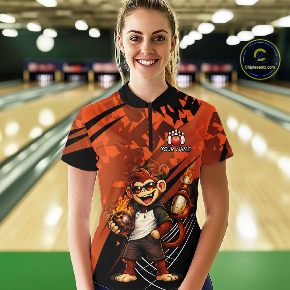 A woman standing in a bowling alley wearing a custom-designed orange and black bowling shirt with a cartoon monkey graphic and 'YOUR NAME' text. 