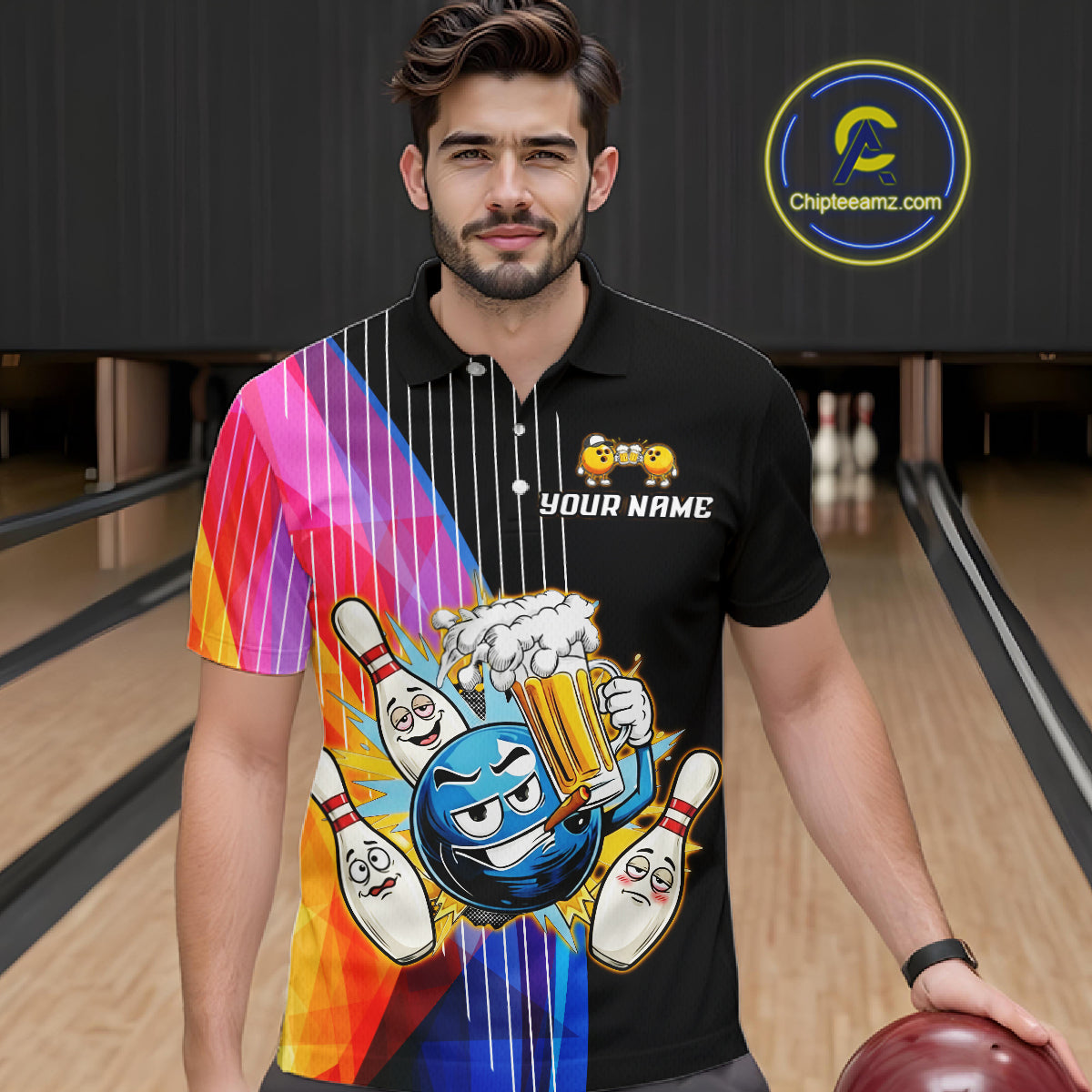 Man wearing a black t-shirt with colorful graphics and text, holding a bowling ball in a bowling alley.