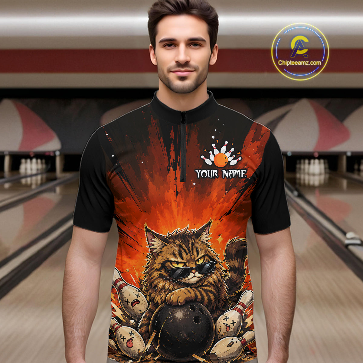 Man wearing a black t-shirt with a colorful design of a cat holding a bowling ball in a bowling alley.