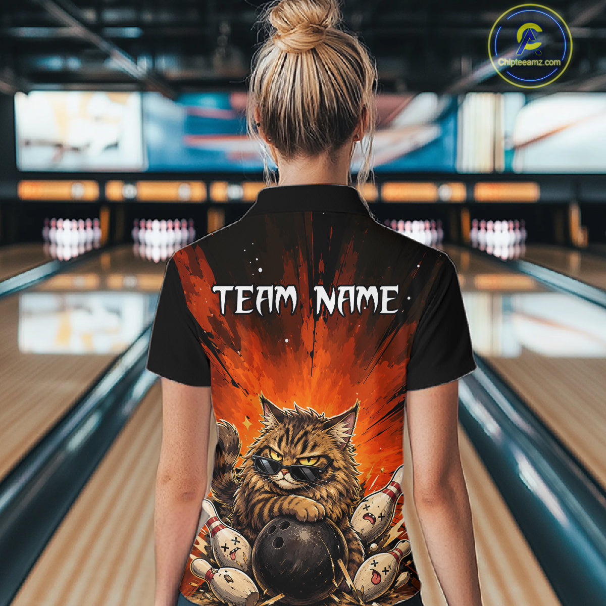 Person wearing a black shirt with a graphic design of a cat and bowling balls in a bowling alley.