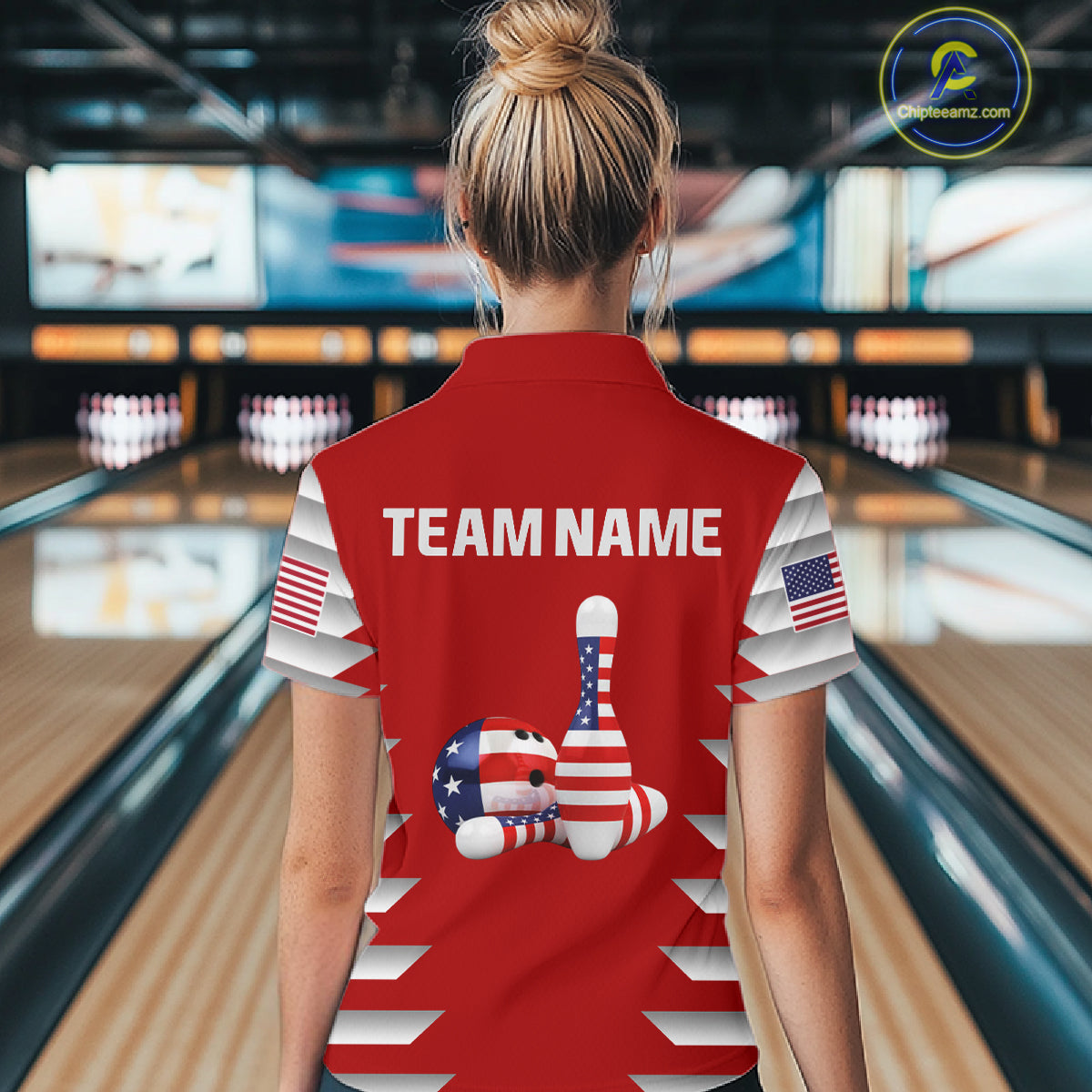 Female model wearing a custom red patriotic bowling polo shirt back view displaying the personalized team name above American flag bowling pins artwork at the bowling alley