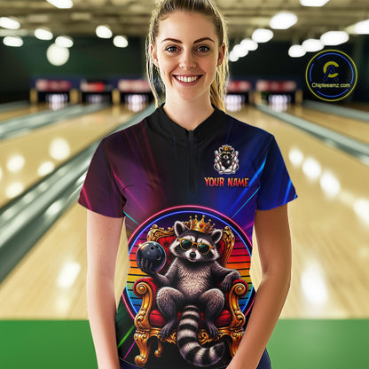 Person wearing a neon bowling shirt with a raccoon design in a bowling alley.