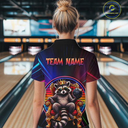 Person wearing a neon shirt with a raccoon graphic and 'TEAM NAME' text in a bowling alley.