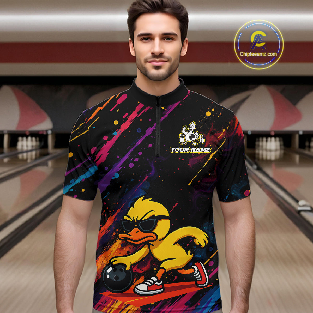A man wearing a short-sleeve black quarter-zip bowling jersey with a colorful paint-splatter design and a cartoon duck graphic on the front, standing in a bowling alley. A circular 'Chipeeamz.