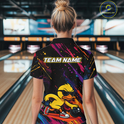 A woman viewed from behind wearing a short-sleeve bowling shirt with a colorful abstract print and a cartoon duck graphic on the back. The shirt has 'TEAM NAME' printed across the upper back, and the bowling alley lanes are visible in the background.