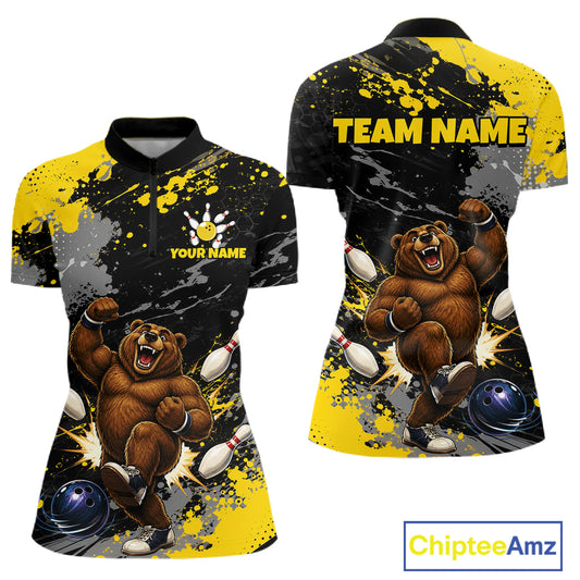 Front and back views of a women's short-sleeve polo shirt with a black, yellow, and gray paint-splatter design featuring a cartoon bear bowling theme. The front shows a black collar, a partial button placket, and customizable text 'YOUR NAME' with a bowling pin hand icon.